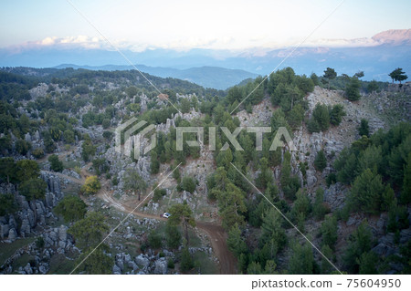Aerial view of rocky mountains with evergreen trees. Aerial view of rocky mountains with evergreen trees. 75604950