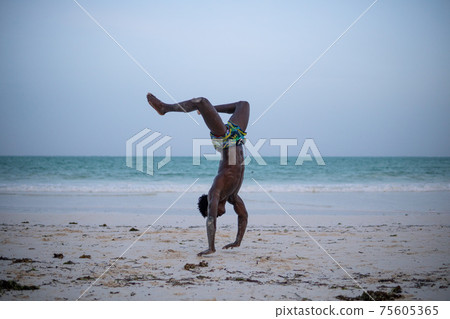 Young Attractive Muscular and Strong Athletic Black African Man at the White Sand Beach Training Body Calisthenics 75605365
