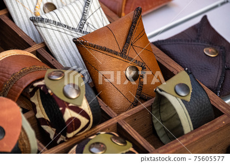Handmade wallets and bracelets, made of leather and fabric, with metal rivets, on a store shelf. Fashion accessory. 75605577