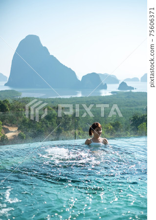 Happy woman in white swimsuit swimming in luxury pool hotel against Phang Nga bay background, Tourist relaxing at Samet Nang She, near Phuket in Southern Thailand. travel, trip and summer vacation Happy woman in white swimsuit swimming in luxury pool hotel against Phang Nga bay background, Tourist relaxing at Samet Nang She, near Phuket in Southern Thailand. travel, trip and summer vacation 75606371