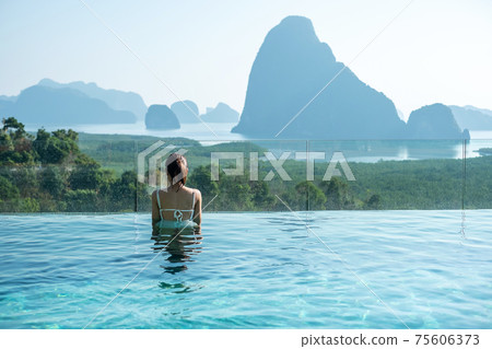 Happy woman in white swimsuit swimming in luxury pool hotel against Phang Nga bay background, Tourist relaxing at Samet Nang She, near Phuket in Southern Thailand. travel, trip and summer vacation Happy woman in white swimsuit swimming in luxury pool hotel against Phang Nga bay background, Tourist relaxing at Samet Nang She, near Phuket in Southern Thailand. travel, trip and summer vacation 75606373