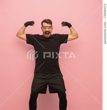 Young athletic man in black sports attire isolated on pink background. Young athletic man in black sports attire isolated on pink background. 75606433