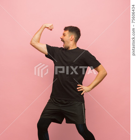 Young athletic man in black sports attire isolated on pink background. Young athletic man in black sports attire isolated on pink background. 75606434