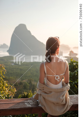 Happy traveler woman enjoy Phang Nga bay view point, alone Tourist sitting and relaxing at Samet Nang She, near Phuket in Southern Thailand. Southeast Asia travel, trip and summer vacation concept 75606440