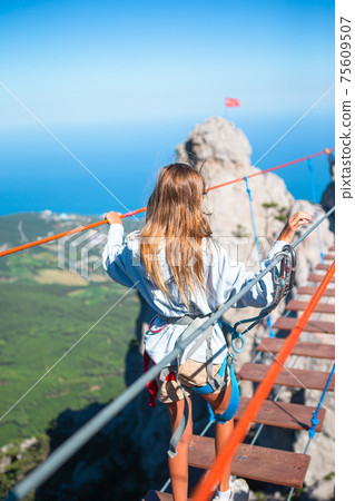 Girls crossing the chasm on the rope bridge. Girls crossing the chasm on the rope bridge. 75609507
