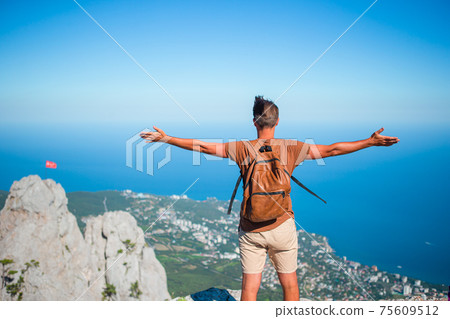 Tourist man outdoor on edge of cliff seashore Tourist man outdoor on edge of cliff seashore 75609512