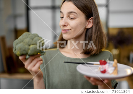 Woman makes a choice between healthy food and sweet dessert Woman makes a choice between healthy food and sweet dessert 75611864