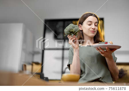 Woman makes a choice between healthy food and sweet dessert Woman makes a choice between healthy food and sweet dessert 75611878