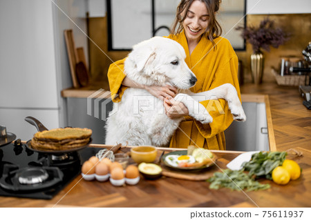 Woman with dog on the kitchen in the morning 75611937