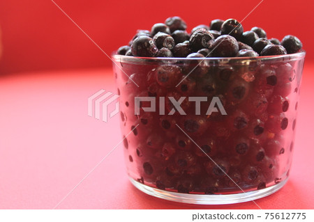berry still life blueberries or currants in a glass on a red background with a place for text and a copyspace view from the side 75612775