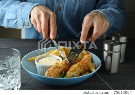 Woman eating fried fish and chips on dark table, close up Woman eating fried fish and chips on dark table, close up 75613004