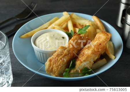 Concept of tasty eating with fried fish and chips on dark textured table Concept of tasty eating with fried fish and chips on dark textured table 75613005