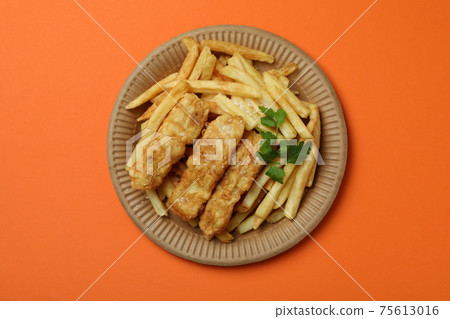 Plate with fried fish and chips on orange background 75613016