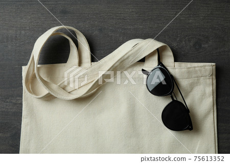 Eco bag with sunglasses on dark textured background 75613352