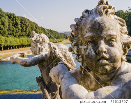 Detail of the fountain of Venus and Adonis with the face of a winged marble cherub in the foreground, Royal Palace of Caserta, Italy Detail of the fountain of Venus and Adonis with the face of a winged marble cherub in the foreground, Royal Palace of Caserta, Italy 75613797