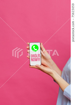 Girl hand holds a smartphone with a handset icon and the inscription order now on a pink background. Girl hand holds a smartphone with a handset icon and the inscription order now on a pink background. 75615059