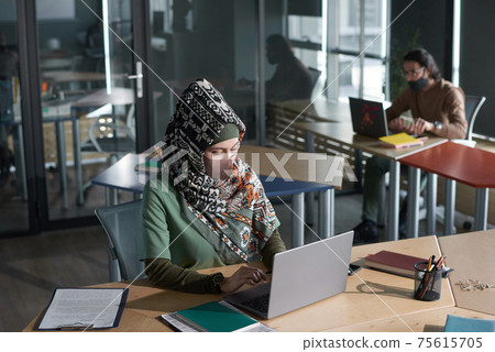 Muslim woman typing on laptop at office Muslim woman typing on laptop at office 75615705