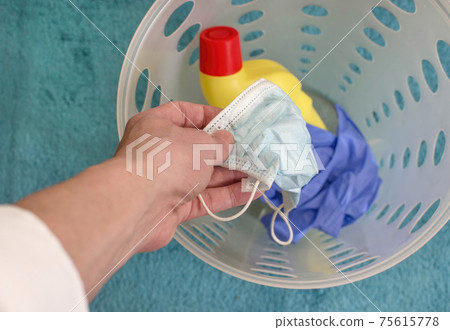 Man hands throwing medical masks, gloves and disinfectant bottle in the trash, end of quarantine and disease coronavirus COVID-19 concept. Selective focus Man hands throwing medical masks, gloves and disinfectant bottle in the trash, end of quarantine and disease coronavirus COVID-19 concept. Selective focus 75615778