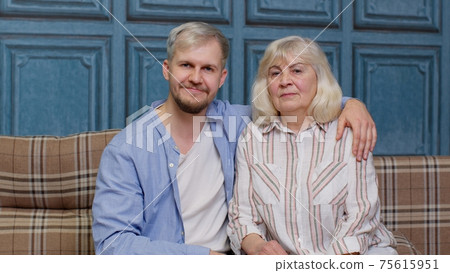 Family of senior mother and handsome adult son or grandson looking at camera, domestic weekends 75615951