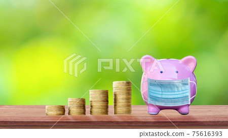 Coins and piggy banks wear anti-virus masks on wooden tables and blurred green background as ideas for spending money during the virus outbreak. Coins and piggy banks wear anti-virus masks on wooden tables and blurred green background as ideas for spending money during the virus outbreak. 75616393