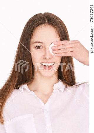 Female teenager person. Cleansing dirty skin. Remove mascara. Cotton pad face 75617241