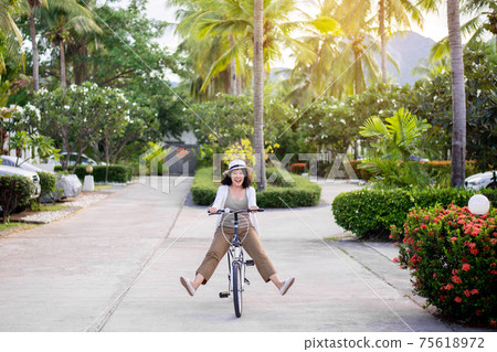 Happy women cycling spreads legs on bicycle at park,Practice pedaling circles,Riding a bike 75618972