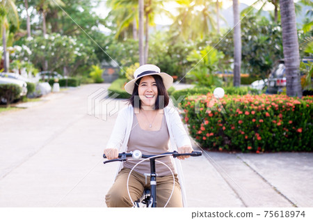 Happy women cycling spreads legs on bicycle at park,Practice pedaling circles,Riding a bike 75618974