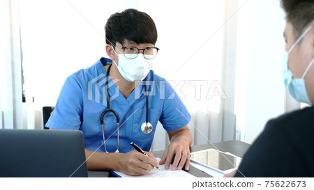 Asian man doctor wear protection face mask during coronavirus and flu outbreak is taking care examining sick patient in hospital Asian man doctor wear protection face mask during coronavirus and flu outbreak is taking care examining sick patient in hospital 75622673