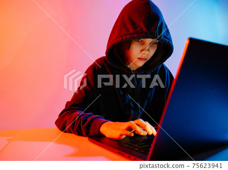 a girl in dark hooded clothes works at night at the computer. Hacker.  75623941