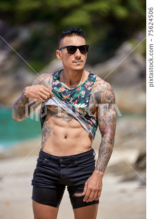Athletic young tattooed guy at the beach 75624506