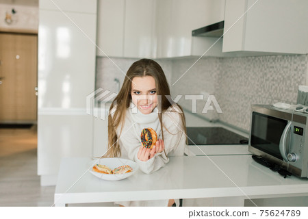 Attractive female with cup of coffee, smartphone and cakes in the bed Attractive female with cup of coffee, smartphone and cakes in the bed 75624789