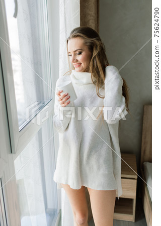Attractive female with cup of coffee, smartphone and cakes in the bed Attractive female with cup of coffee, smartphone and cakes in the bed 75624790