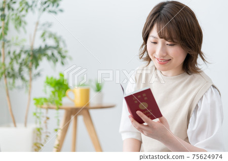 Young woman looking at her passport in the living room Young woman looking at her passport in the living room 75624974