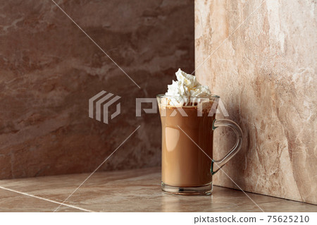 Glass cup of coffee latte on a beige ceramic table. Glass cup of coffee latte on a beige ceramic table. 75625210