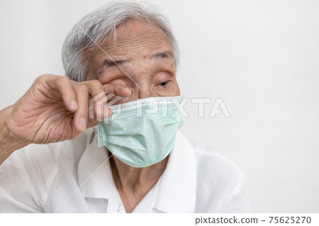 Asian senior woman in medical protective mask rubbing her eyes,Do not touch eyes with her dirty hand,avoid touching to protect form COVID-19,risk of Coronavirus infection,Don't touch face,health care 75625270