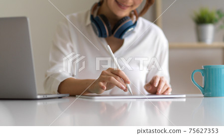 Close up view of female hand with stylus pen working on digital tablet 75627353