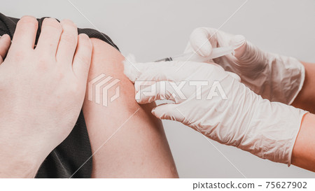 Vaccination close up, injection of vaccine in hand, doctor in white gloves. Vaccination close up, injection of vaccine in hand, doctor in white gloves. 75627902