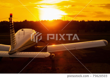 Rear view of a parked small plane on a sunset background. Silhouette of a private airplane landed at dusk. Rear view of a parked small plane on a sunset background. Silhouette of a private airplane landed at dusk. 75628503