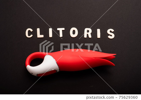 An overhead view of a red tulip shaped clitoral vibrator and the inscription clitoris on a black background 75629360