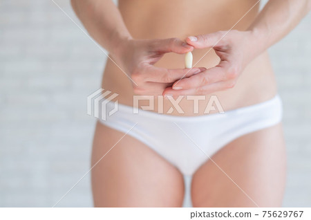 Faceless Caucasian woman in white panties and with a bare belly holds a healing candle. Girl demonstrates anal or vaginal suppository. Prescription from a gynecologist for women's health. Faceless Caucasian woman in white panties and with a bare belly holds a healing candle. Girl demonstrates anal or vaginal suppository. Prescription from a gynecologist for women's health. 75629767