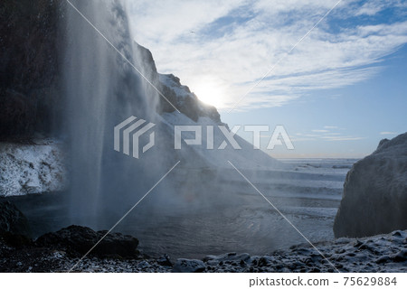 Seljalandsfoss waterfall view in winter in Scandinavian Iceland (waterfall basin, sunset and blue sky) Seljalandsfoss waterfall view in winter in Scandinavian Iceland (waterfall basin, sunset and blue sky) 75629884