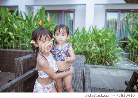 two girl in swim wear smiling looking at camera two girl in swim wear smiling looking at camera 75630410
