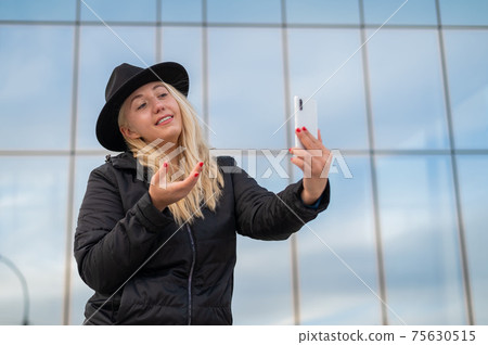 Deaf-mute young woman and speaks sign language over video communication on the phone outdoors Deaf-mute young woman and speaks sign language over video communication on the phone outdoors 75630515