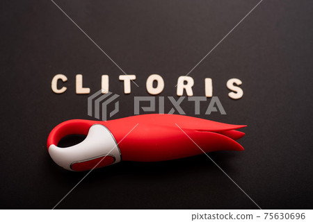 An overhead view of a red tulip shaped clitoral vibrator and the inscription clitoris on a black background An overhead view of a red tulip shaped clitoral vibrator and the inscription clitoris on a black background 75630696
