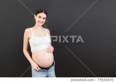 pregnant belly at colorful background with copy space. Expecting mother in opened jeans. Motherhood concept 75630870
