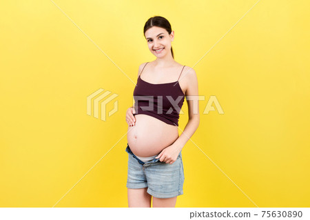 pregnant woman in unzipped jeans showing her naked belly at colorful background with copy space. Baby expecting concept pregnant woman in unzipped jeans showing her naked belly at colorful background with copy space. Baby expecting concept 75630890