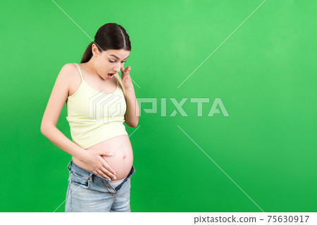 pregnant woman in unzipped jeans showing her naked abdomen at colorful background with copy space 75630917