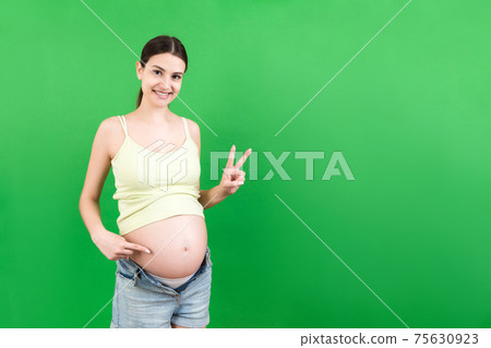 Young beautiful teenager girl pregnant expecting baby over isolated colored background smiling showing big belly Young beautiful teenager girl pregnant expecting baby over isolated colored background smiling showing big belly 75630923