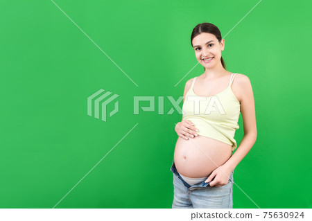 pregnant woman in unzipped jeans showing her baby bump at colorful background with copy space. Waiting for a baby concept pregnant woman in unzipped jeans showing her baby bump at colorful background with copy space. Waiting for a baby concept 75630924