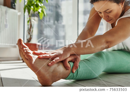 Closeup of mindful African woman stretching her body while practicing Yoga at home 75633503